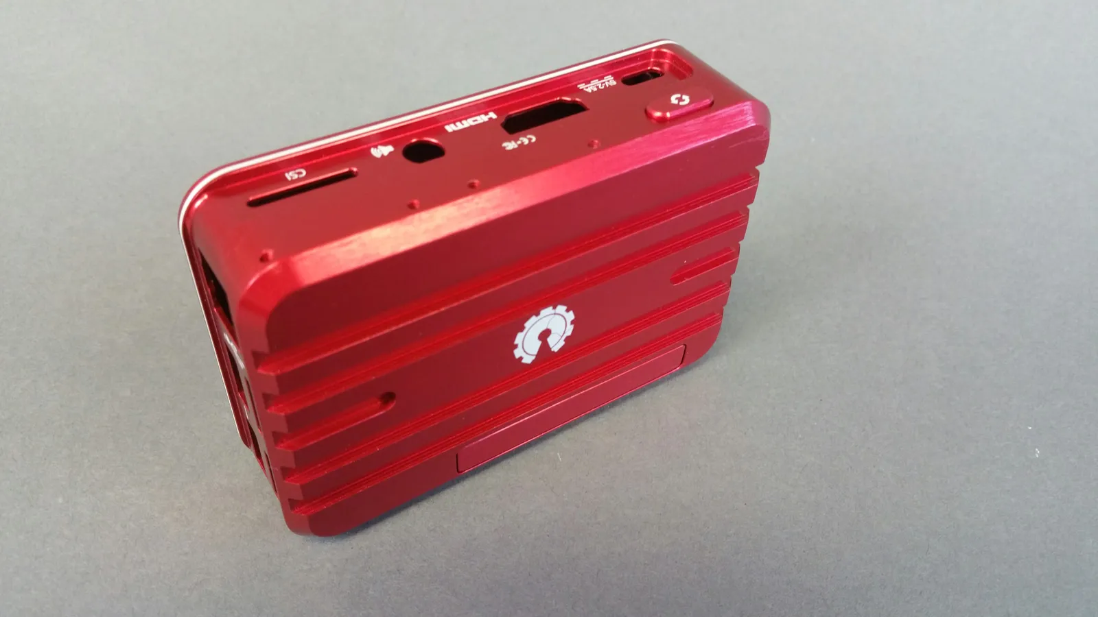 Photo originale du projet montrant un boîtier électronique rouge en aluminium usiné avec des nervures et des ouvertures identifiées pour les ports.
