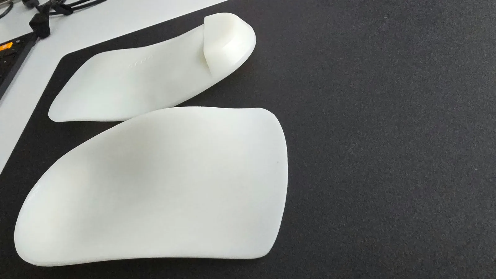 A pair of white SLS-printed orthotic insoles.