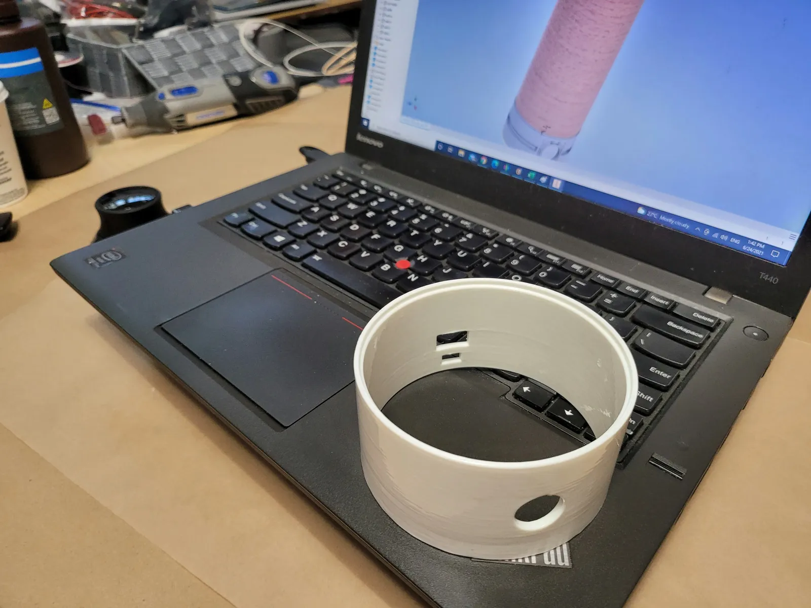 Prototype cylindrique blanc à côté de son modèle CAO affiché sur un ordinateur portable.