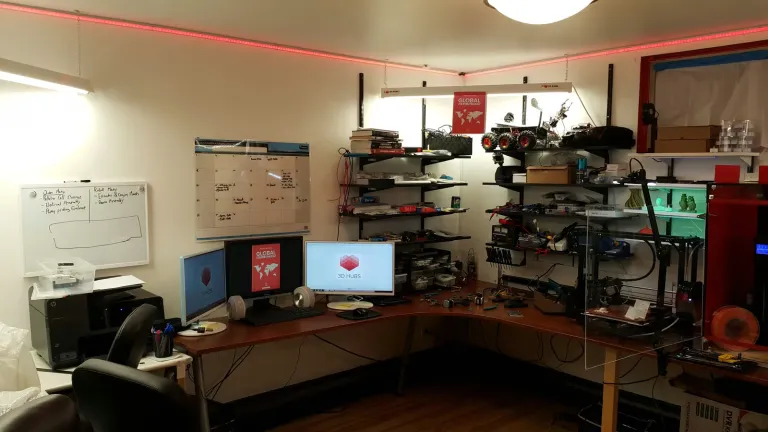 Engineering workstation with dual monitors, whiteboard, electronics shelves and 3D printers