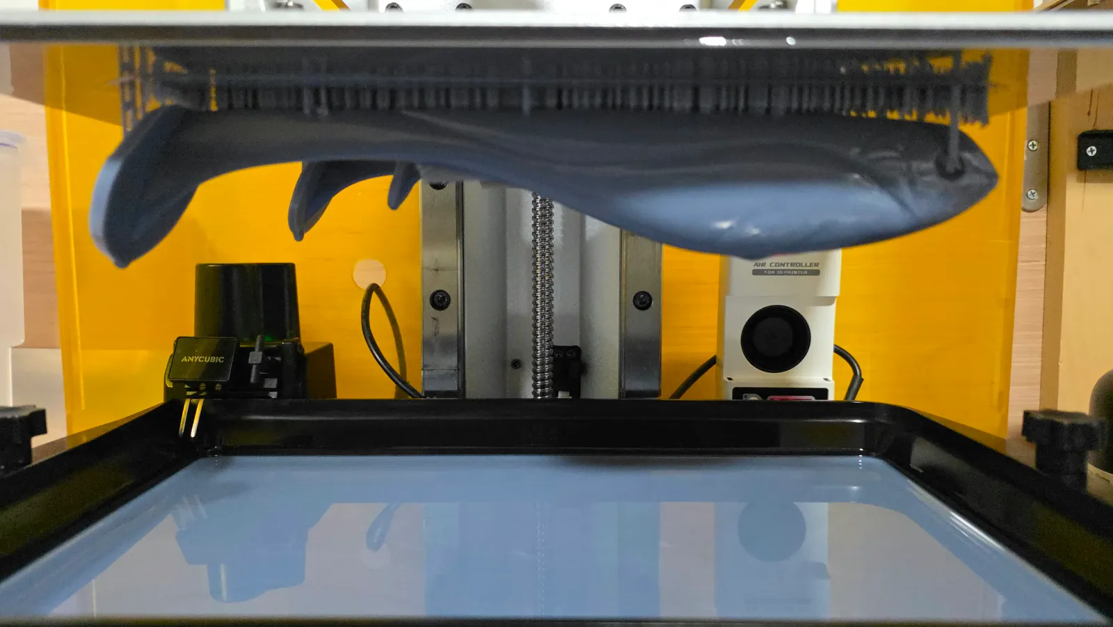 Resin 3D printer with a large grey supported print hanging from the build plate over the vat