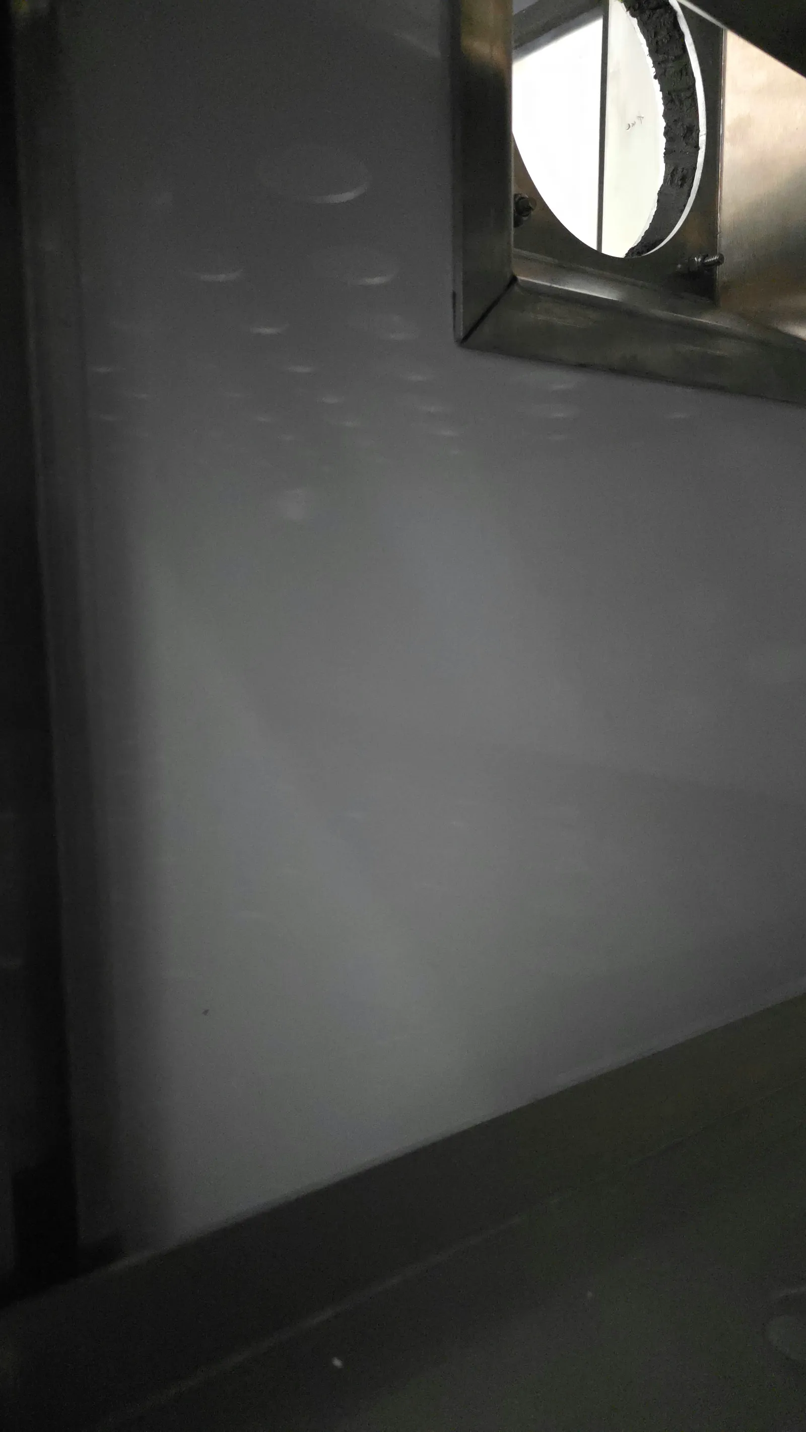 Gros plan du lit de poudre dans la chambre de fabrication d'une imprimante 3D SLS, avec les contours à peine visibles de pièces imbriquées dans la poudre