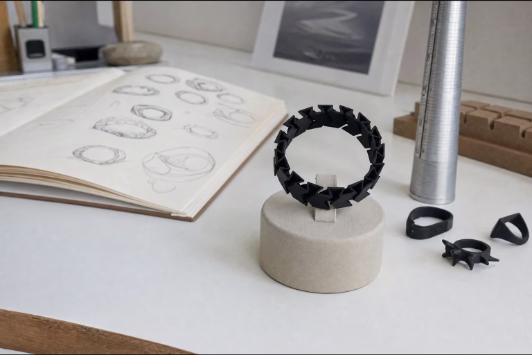 Bague flexible noire à pointes imprimée en 3D sur un présentoir, à côté d'autres prototypes de bagues